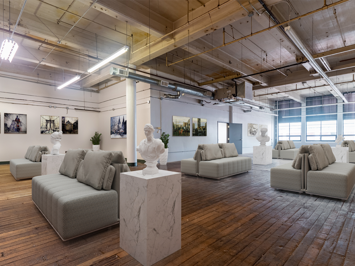 open area staged as art gallery with paintings on the walls and seating area