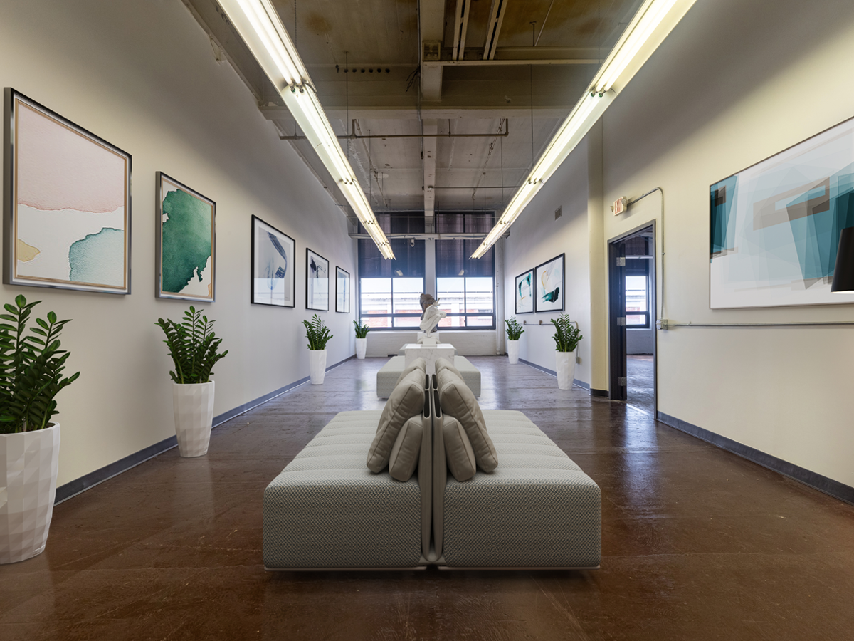 open area staged as art gallery with paintings on the walls and seating area